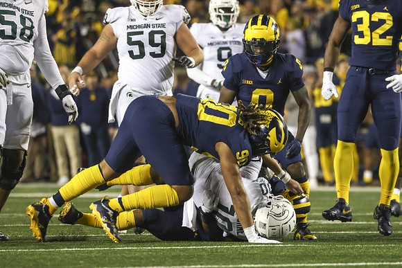 Mike Morris (90), Mike Sainristil (0), and Jaylen Harrell (32)