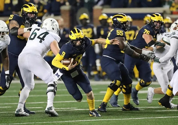 Zak Zinter (65), J.J. McCarthy (9), Olusegun Oluwatimi (55), and Ryan Hayes (76)