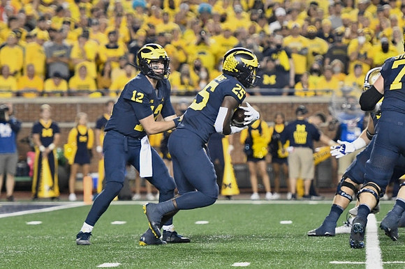 Cade McNamara (12), Hassan Haskins (25), and Andrew Stueber (71)