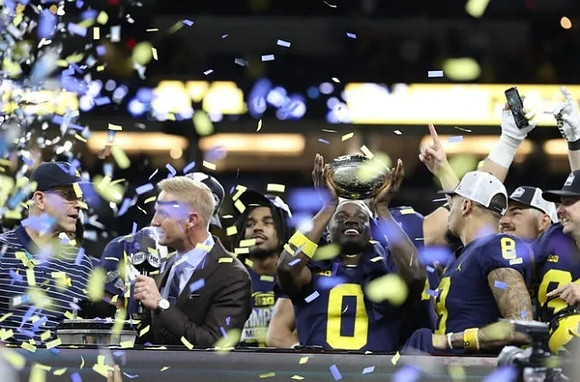 Jim Harbaugh, Mike Sainristil (0), Ronnie Bell (8), Jake Moody (13), and Big Ten Championship Trophy