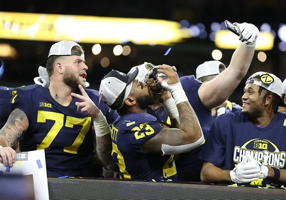 Trevor Keegan (77), Michael Barrett (23), and Big Ten Championship Trophy
