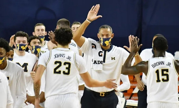 Brandon Johns Jr. (23), Juwan Howard, Chaundee Brown Jr. (15), and Michigan Team