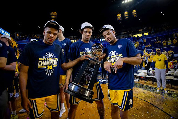 Trey McKenney (1), Yaxel Lendeborg (23), Roddy Gayle Jr. (11), and Big Ten Championship Trophy