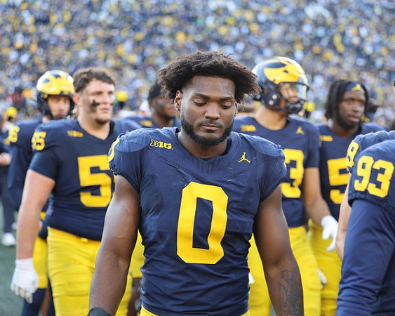 Mason Graham (55), Josaiah Stewart (0), and Michigan Team