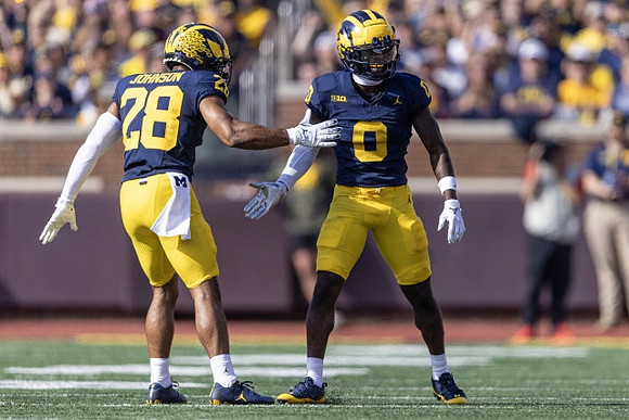 Quinten Johnson (28) and Mike Sainristil (0)