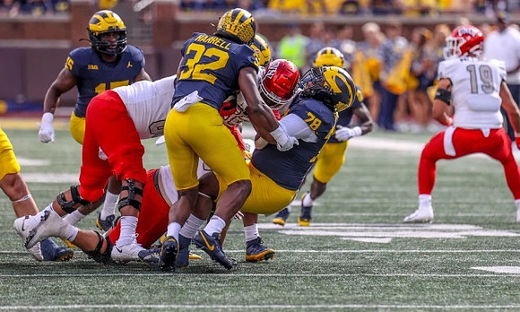 Ernest Hausmann (15), Jaylen Harrell (32), Kenneth Grant (78), and Mike Sainristil (0)