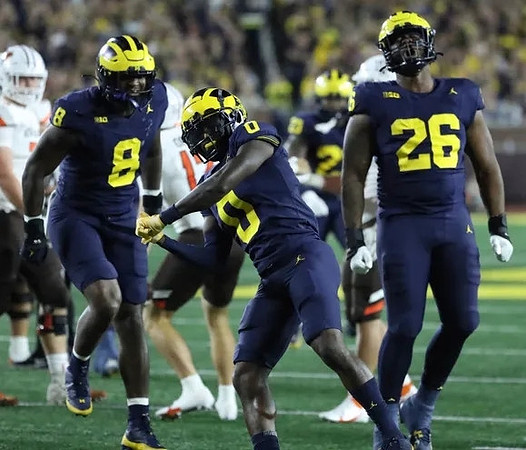 Derrick Moore (8), Mike Sainristil (0), and Rayshaun Benny (26)
