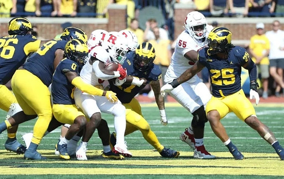 Mike Sainristil (0) and Junior Colson (25)