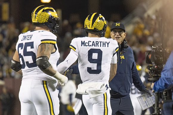 Zak Zinter (65), J.J. McCarthy (9), and Jim Harbaugh