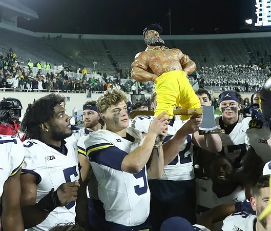 J.J. McCarthy (9), Paul Bunyan Trophy, and Michigan Team