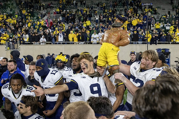 J.J. McCarthy (9), Paul Bunyan Trophy, and Michigan Team