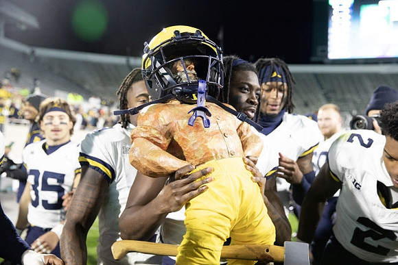Rod Moore (9), Paul Bunyan Trophy, and Michigan Team