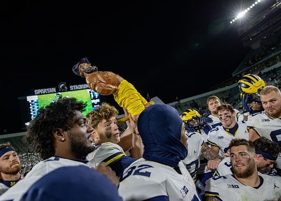 J.J. McCarthy (9), Paul Bunyan Trophy, and Michigan Team
