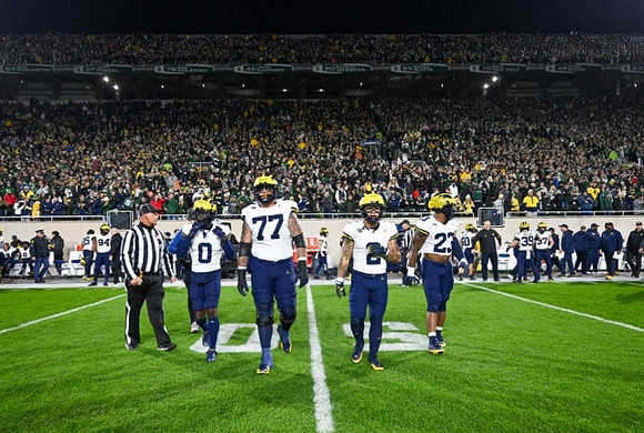 Mike Sainristil (0), Trevor Keegan (77), Blake Corum (2), and Michael Barrett (23)
