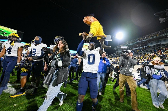 Mike Sainristil (0) and Paul Bunyan Trophy