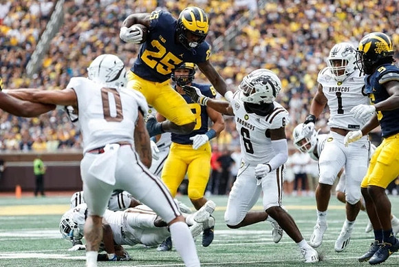 Hassan Haskins (25), Matthew Hibner (88), and Mike Sainristil (5)