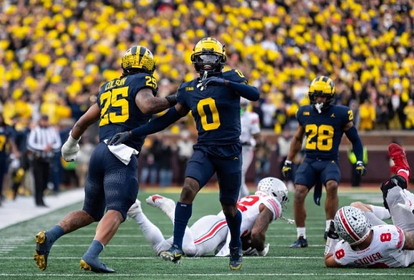 Junior Colson (25), Mike Sainristil (0), and Quinten Johnson (28)