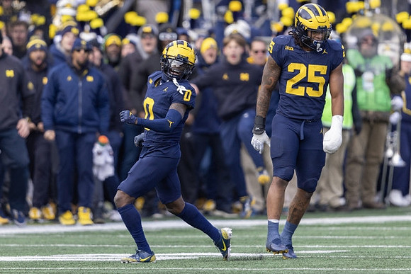 Mike Sainristil (0) and Junior Colson (25)