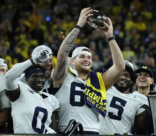 Mike Sainristil (0), Zak Zinter (65), Josaiah Stewart (5), Jim Harbaugh, and Big Ten Championship Trophy