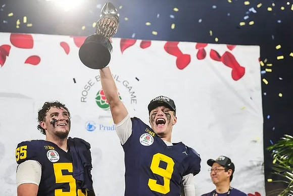 Mason Graham (55), J.J. McCarthy (9), and UofM President Santa Ono