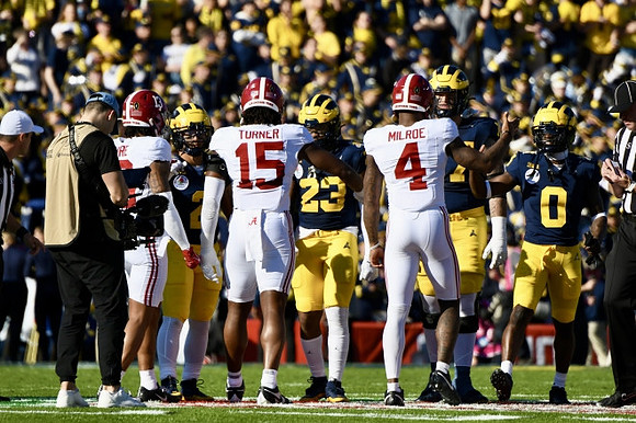 Blake Corum (2), Michael Barrett (23), Trevor Keegan (77), and Mike Sainristil (0)