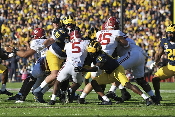 Mason Graham (55), Mike Sainristil (0), and Junior Colson (25)