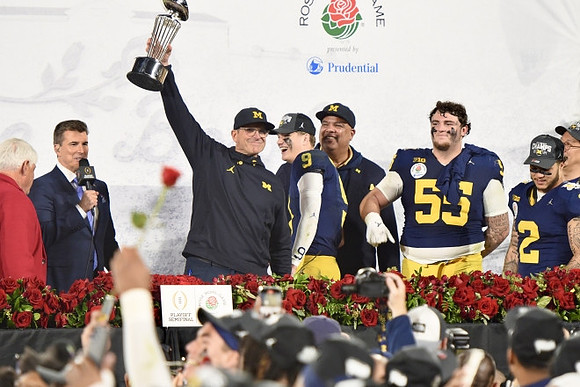 J.J. McCarthy (9), Jim Harbaugh, Blake Corum (2), Mason Graham (55), Warde Manuel, UofM President Santa Ono, and Rose Bowl Trophy
