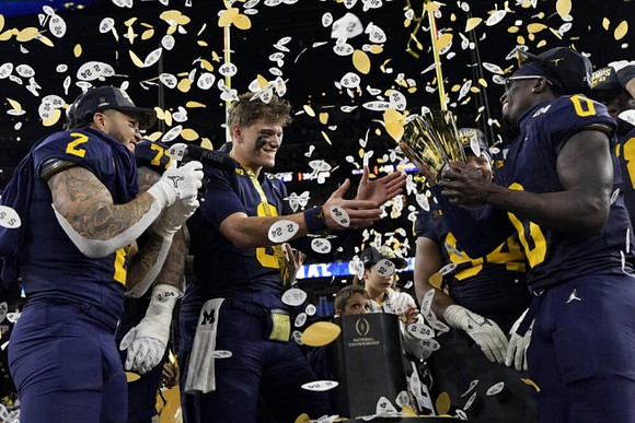 Blake Corum (2), J.J. McCarthy (9), Kris Jenkins (94), Mike Sainristil (0), and National Championship Trophy