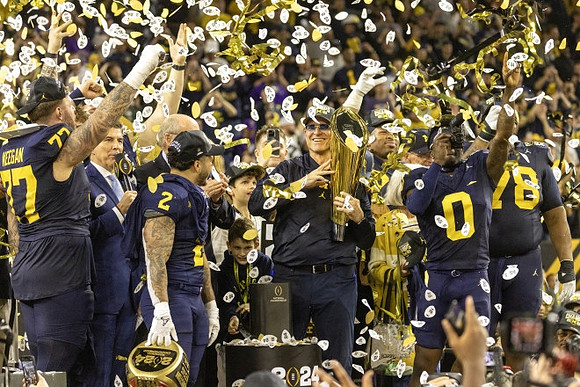 Trevor Keegan (77), Blake Corum (2), Jim Harbaugh, Mike Sainristil (0), Kenneth Grant (78), and National Championship Trophy