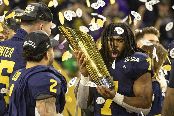 Blake Corum (2), Zak Zinter (65), Donovan Edwards (7), and National Championship Trophy