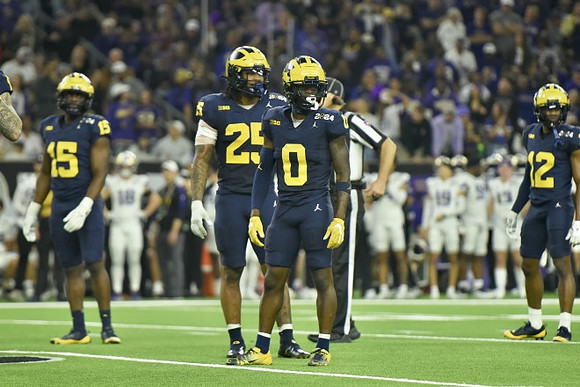 Ernest Hausmann (15), Junior Colson (25), Mike Sainristil (0), and Josh Wallace (12)
