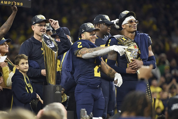 Jim Harbaugh, Blake Corum (2), Kenneth Grant (78), Will Johnson (2), and National Championship Trophy