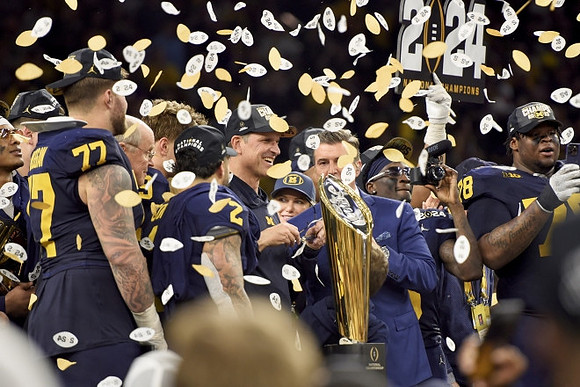 Trevor Keegan (77), Blake Corum (2), Jim Harbaugh, Mike Sainristil (0), Kenneth Grant (78), and National Championship Trophy