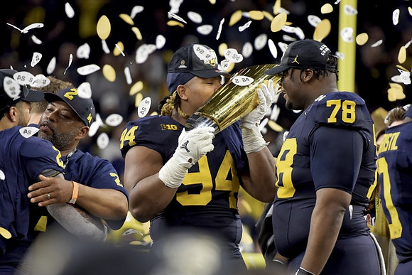 Blake Corum (2), Kris Jenkins (94), Kenneth Grant (78), and National Championship Trophy