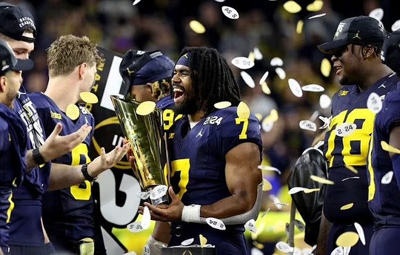 Zak Zinter (65), J.J. McCarthy (9), Kris Jenkins (94), Donovan Edwards (7), Kenneth Grant (78), and National Championship Trophy
