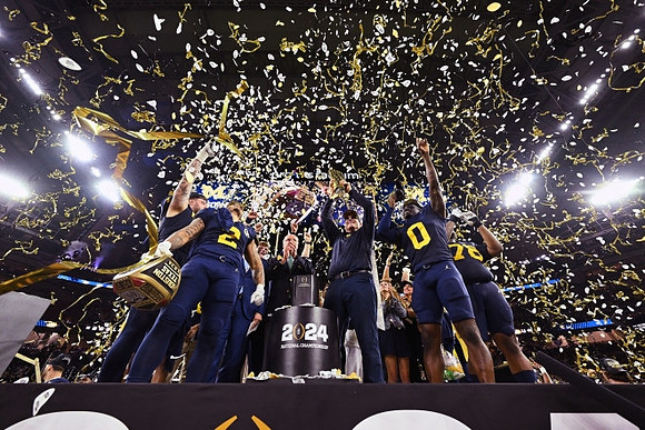 Trevor Keegan (77), Blake Corum (2), Jim Harbaugh, Mike Sainristil (0), Kenneth Grant (78), and National Championship Trophy