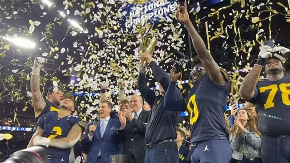 Trevor Keegan (77), Blake Corum (2), J.J. McCarthy (9), Jim Harbaugh, Mike Sainristil (0), Kenneth Grant (78), and National Championship Trophy
