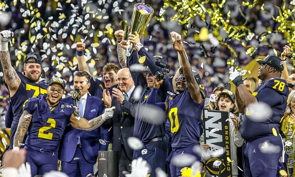 Trevor Keegan (77), Blake Corum (2), J.J. McCarthy (9), Jim Harbaugh, Mike Sainristil (0), Kenneth Grant (78), and National Championship Trophy