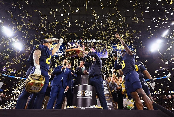 Blake Corum (2), Jim Harbaugh, Mike Sainristil (0), and National Championship Trophy