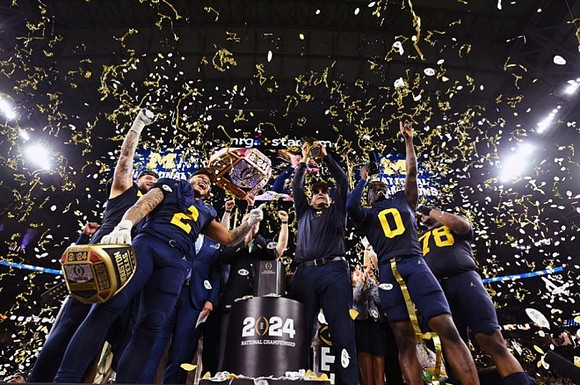 Trevor Keegan (77), Blake Corum (2), Jim Harbaugh, Mike Sainristil (0), Kenneth Grant (78), and National Championship Trophy