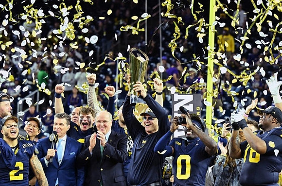 Blake Corum (2), UofM President Santa Ono, J.J. McCarthy (9), Jim Harbaugh, Mike Sainristil (0), Kenneth Grant (78), and National Championship Trophy