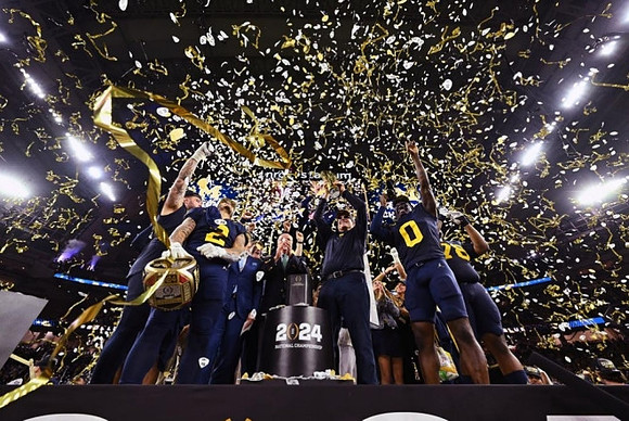 Trevor Keegan (77), Blake Corum (2), Jim Harbaugh, Mike Sainristil (0), Kenneth Grant (78), and National Championship Trophy