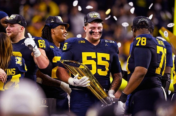 Drake Nugent (60), Junior Colson (25), Mason Graham (55), Kenneth Grant (78), and National Championship Trophy