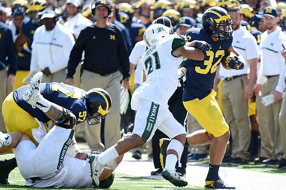 Mason Cole (52), Ty Isaac (32), and Jim Harbaugh