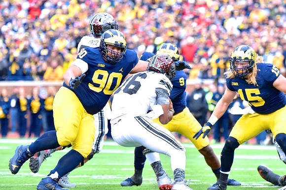 Bryan Mone (90), Mike McCray (9), and Chase Winovich (15)
