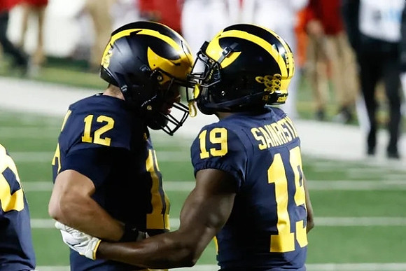 Cade McNamara (12) and Mike Sainristil (19)
