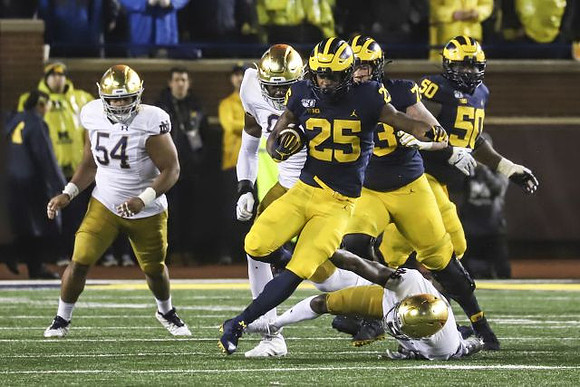 Hassan Haskins (25), Jalen Mayfield (73), and Michael Onwenu (50)