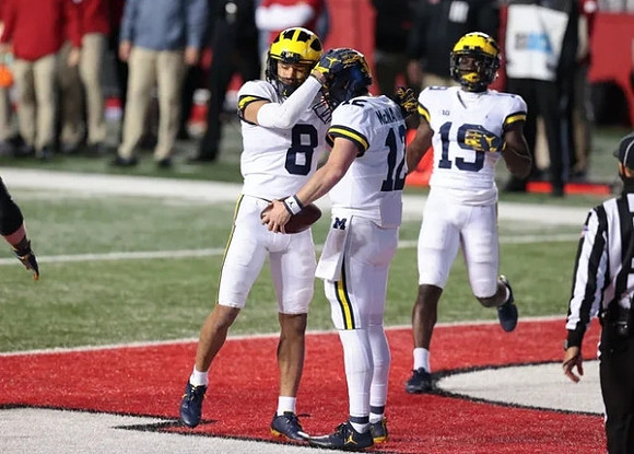 Ronnie Bell (8), Cade McNamara (12), and Mike Sainristil (19)
