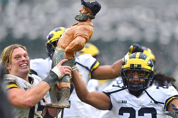 Chase Winovich (15), Tyree Kinnel (23), and Paul Bunyan Trophy