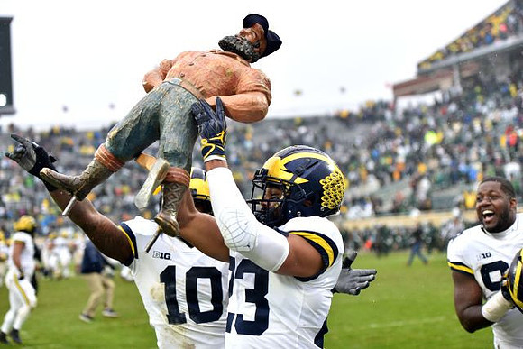 Devin Bush (10), Tyree Kinnel (23), and Paul Bunyan Trophy